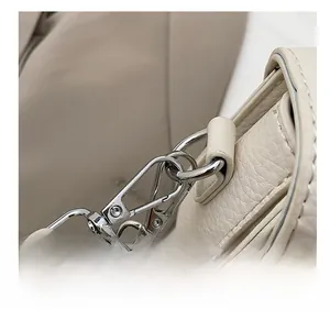 Detail der silbernen Metallhaken an der cremefarbenen Ledertasche mit Litchi-Prägung