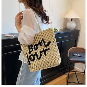 Détail du sac cabas en paille tissée avec broderie Bonjour noire et bandoulière souple