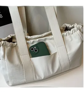 Close-up of cream canvas tote bag showing the front pocket holding a green smartphone