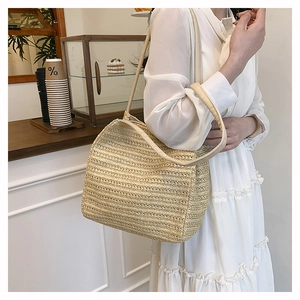 Detail shot of beige woven tote bag with stripe texture on model's shoulder in cafe