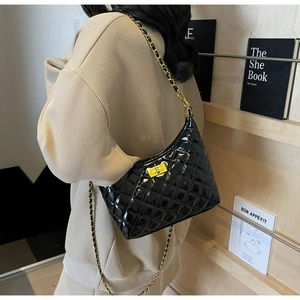 Detail of black quilted leather shoulder bag with gold chain strap and square turn-lock