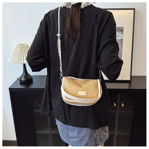 Detail of woven crescent crossbody bag with chain strap shown in modern interior scene