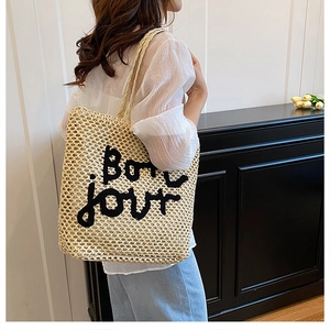 Détail d'un grand sac cabas en paille tissée avec broderie Bon jour sur un mannequin
