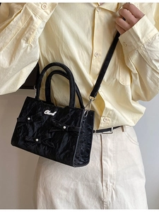 Sac à main plissé noir élégant avec nœuds et perles présenté dans une vue de côté