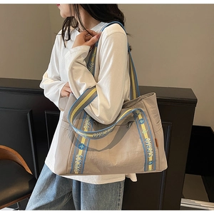 Detail of spacious tote bag with blue and yellow jacquard shoulder strap and side pocket