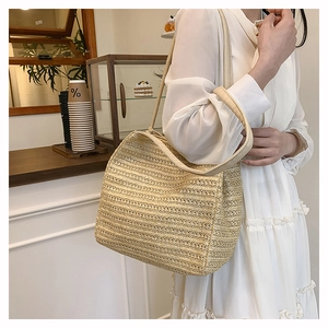 Detail of hand-woven straw tote bag with wide strap on model in white dress