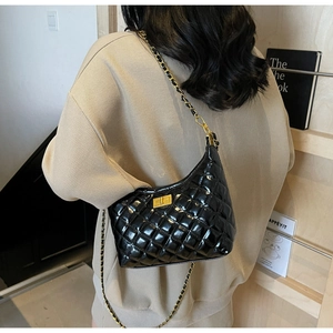 Close-up of a glossy quilted shoulder bag with gold chain and square twist-lock buckle