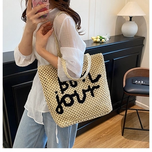 Détail du sac cabas en paille tissée avec texte Bonjour brodé en noir sur beige naturel