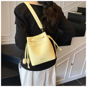 Pale yellow lychee grain leather bucket bag with fashion lettering on a model
