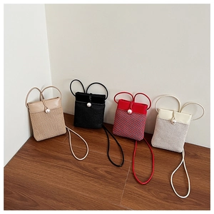 Close-up of woven straw crossbody bags with pearl button closures in four colors