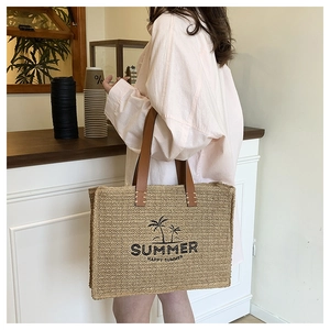 Detail of straw woven tote bag featuring Summer print and brown leather handles in a cafe