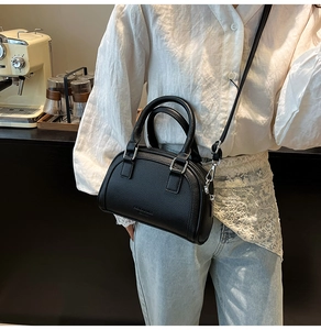 Gros plan du sac bowling noir à motif litchi avec ferrures argentées et bandoulière réglable