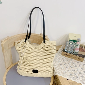 Detailed shot of beige woven tote bag with black leather straps on a wooden chair