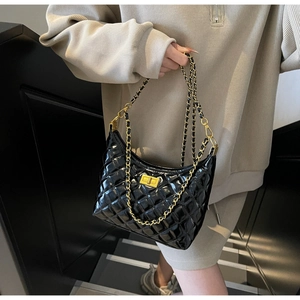 Close-up of quilted black patent leather texture and vintage gold metal twist lock