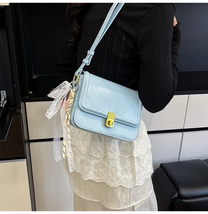 Close-up of light blue leather crossbody bag with gold twist lock and silk scarf detail
