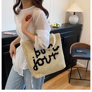 Détail du sac cabas en paille tressée avec broderie bonjour noire pour look estival chic
