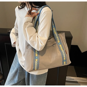 Close-up of a large tote bag featuring a blue and yellow contrast wide shoulder strap
