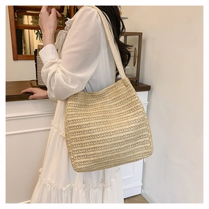 Detailed texture of a woven straw tote bag held by a model in a white dress