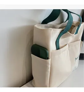 Detail view of the side pocket on this cream canvas tote bag with minimalist cat print