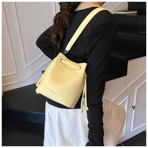 Close-up of vibrant yellow bucket bag in lychee pattern leather with drawstring detail