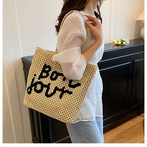 Gros plan du sac fourre-tout en paille beige avec broderie Bon jour et texture