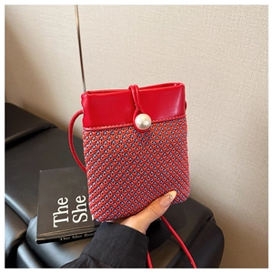 Detail of woven mini bag featuring red and blue texture with a large pearl buckle