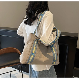 Close-up of beige tote bag side pocket with floral patterned wide canvas shoulder strap