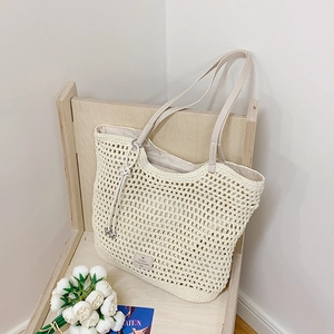 Detail view of a beige woven crochet tote bag with leather straps and interior lining