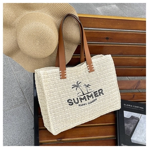 Close-up of summer woven straw tote bag with brown leather handles and palm tree print