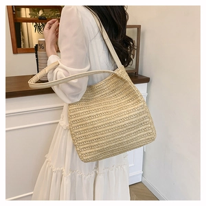 Detail view of woven straw tote bag with cream PU leather straps on model shoulder