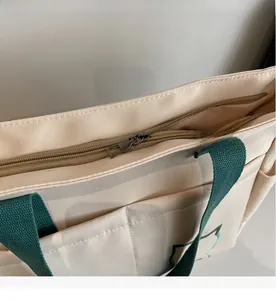 Close-up of smooth nylon zipper closure on a beige canvas tote bag with green handles