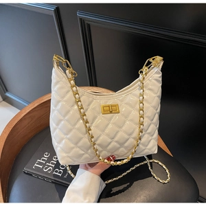 Close-up of white quilted handbag with golden chain strap and metallic twist-lock