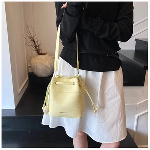 Close-up of the yellow drawstring bucket bag showing its premium litchi leather texture