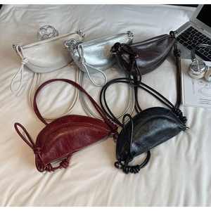Flat lay of multiple crescent hobo bags in various colors with lifestyle accessories