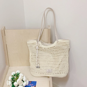 Detail view of cream woven beach tote bag with mesh pattern and leather patch on wood chair