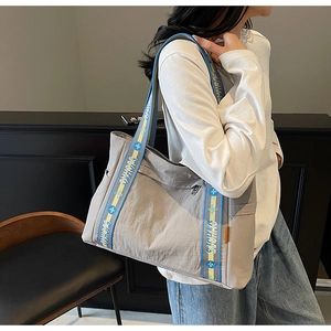 Detail of grey tote bag with blue and yellow floral patterned wide shoulder strap