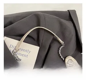 Detail of off-white tote bag featuring silver chain straps and metallic eyelets on leather