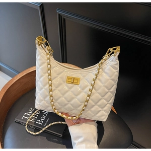 Detail of white quilted crossbody bag with golden chain strap and metallic lock clasp