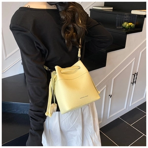 Detailed view of yellow pebbled leather bucket bag with fashion print and drawstring closure
