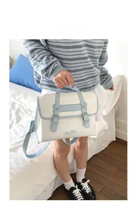 Detail of cream and blue PU leather handbag with adjustable strap and metal buckles