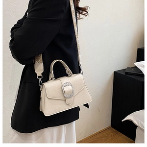 Detail der cremeweißen Handtasche mit Litschi-Muster und breitem Jacquard-Schultergurt