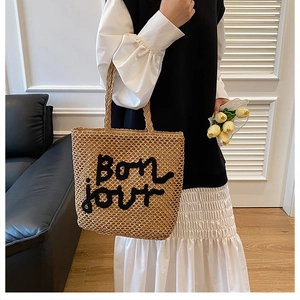 Détail du sac cabas en paille tressée avec broderie Bonjour noire et anses tressées