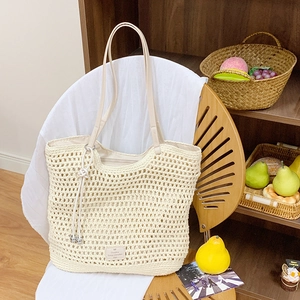 Close-up of beige woven tote bag detailing the hollow crochet pattern and leather strap