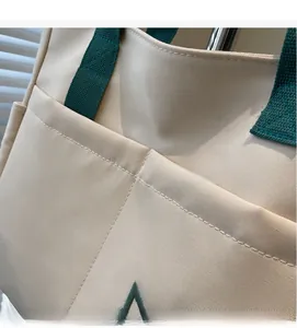 Close-up of beige canvas tote bag showing star embroidery and durable green fabric handles