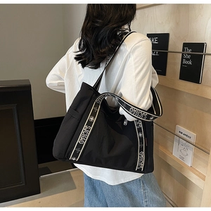 Detail view of black tote bag featuring wide SJCHAO logo shoulder strap and nylon fabric