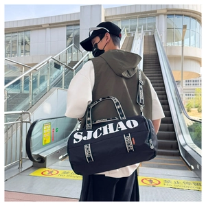 Outdoor lifestyle shot of a black cylindrical travel bag with SJCHAO logo and shoulder strap