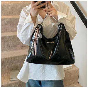 Glossy black hobo bag with silver chain strap and tennis racket charm shown on model