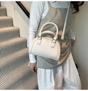 Détail d'un sac en cuir blanc avec motif litchi, boucles argentées et logo embossé