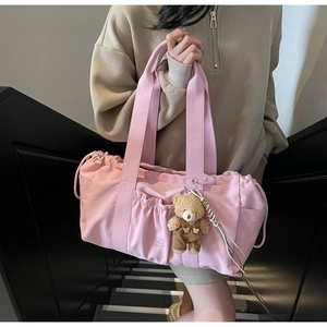Detail view of pink canvas tote bag featuring front pocket and cute bear charm decoration