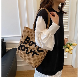 Détail du sac cabas en paille tissée main avec lettrage BONJOUR brodé noir élégant